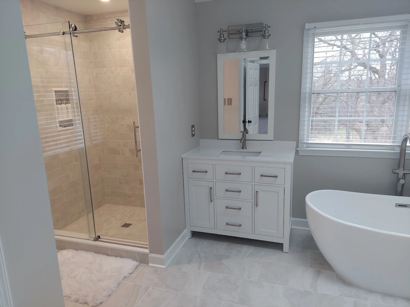 a modern bathroom remodel with stone accents and white furniture.